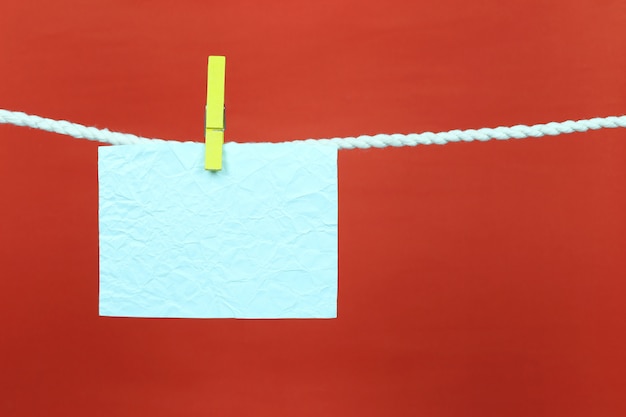 Photo papier vide note bleu accrocher sur la corde à linge.