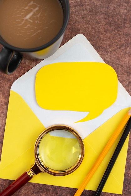 Photo papier vierge avec des crayons d'enveloppe en forme de bulle de parole, une tasse de café et une loupe sur la table, il représente des stratégies de marketing importantes pour les objectifs commerciaux