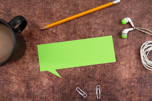 Photo papier vierge en forme de bulle de pensée avec un crayon, une tasse de café, un trombone et un casque note de table en bois avec dispositif d'écoute représentant la communication de vos opinions