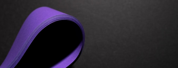 Papier violet déformé sur une surface violette sur fond noir