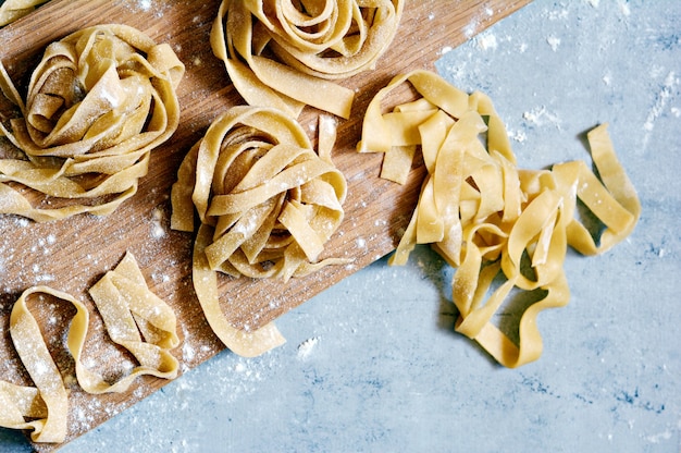 Pappardelle, fettuccine ou tagliatelle de pâtes italiennes jaunes crues