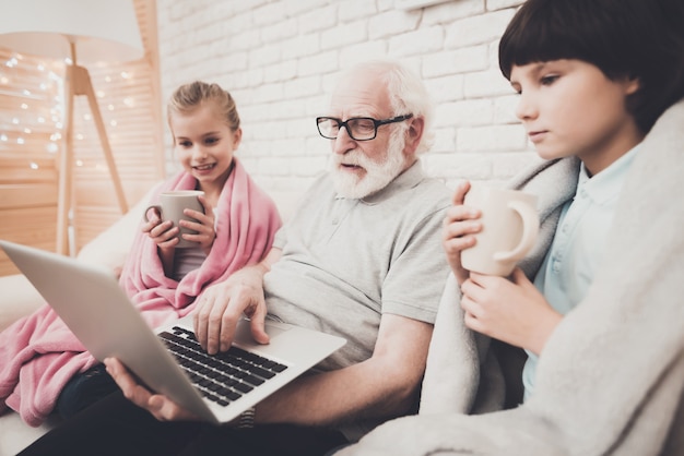 Photo papy et ses enfants regardent un film boivent du thé à la maison