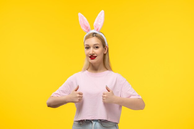 Pâques belle blonde adorable fille avec des oreilles de lapin rose et rouge à lèvres souriant avec un bon geste