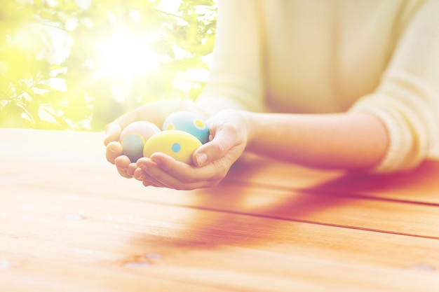 Pâques, fêtes, traditions et concept de personnes - gros plan de mains de femmes tenant des œufs de Pâques colorés