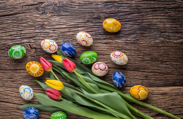 Pâques. Oeufs de pâques faits à la main et tulipes printanières sur une vieille table en bois.