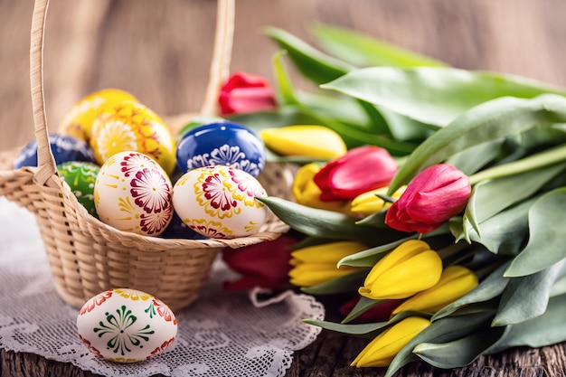 Pâques. Oeufs de pâques peints à la main dans un panier et des tulipes printanières.