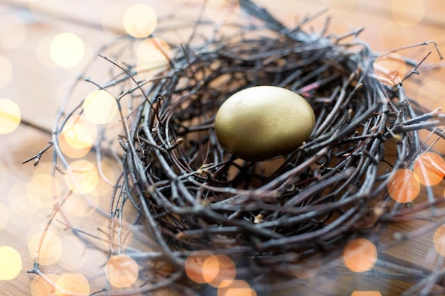 pâques, vacances, tradition et concept d'objet - gros plan d'oeufs de pâques dorés dans un nid sur une surface en bois