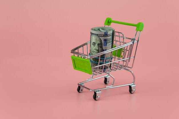 Un paquet de billets d'un dollar dans un chariot de supermarché sur fond clair