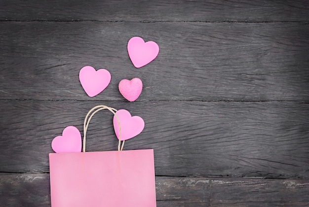 Paquet cadeau avec coeur sur fond en bois. sac rose avec coeur rose avec espace copie