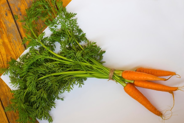 Paquet de carottes sur fond blanc et en bois vue de dessus