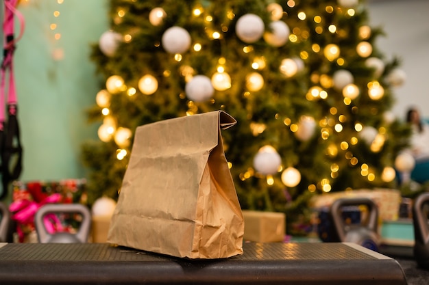 paquet de livraison avec des aliments sains, du poids et des haltères sur fond d'arbre de noël