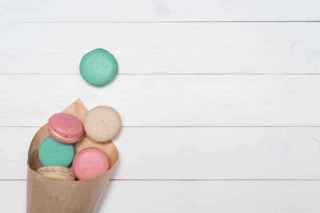 Paquet de macarons colorés sur fond blanc en bois