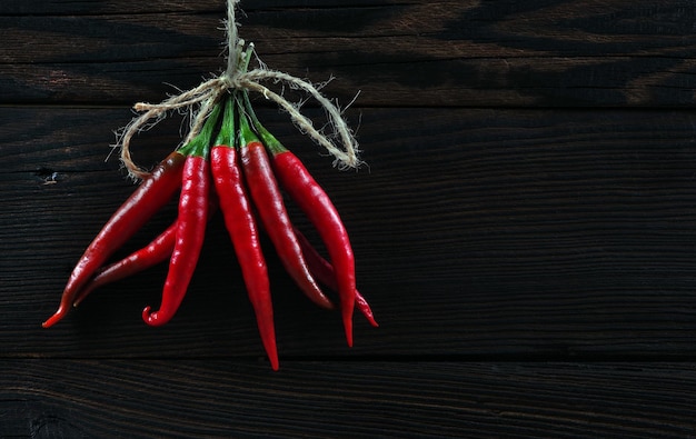 Un paquet de poivrons rouges suspendu à une corde.