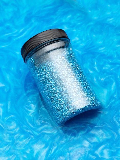 Un paquet de sel de cristal bleu scintillant pour se détendre dans le bain Pot de sel de mer bleu scintillant dans de l'eau colorée L'idée d'un traitement à domicile aromathérapie et soins personnels Cosmétiques soins de beauté