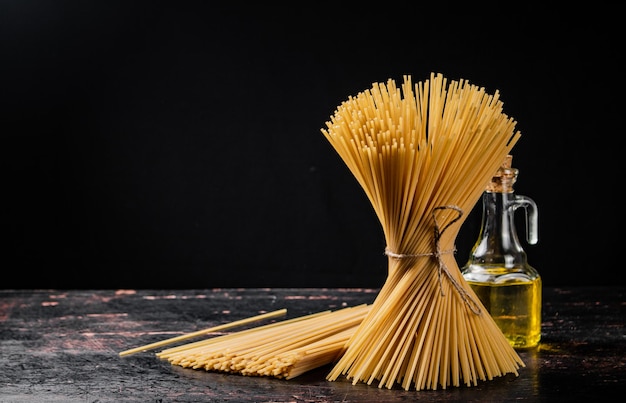 Un paquet de spaghettis secs attachés avec une corde se dresse sur la table