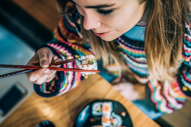 Par dessus Crop woman eating sushi