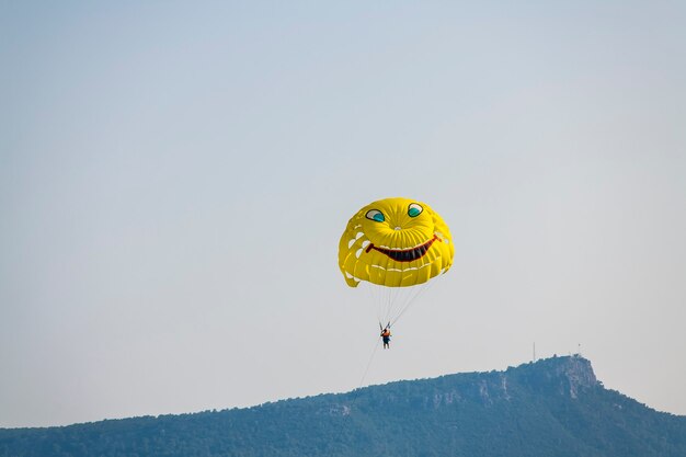 Parachute jaune avec un touriste volant à travers le ciel bleu d'été