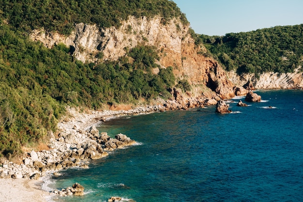 Photo le paradis est une plage rocheuse dans l'eau de mer bleue du monténégro et les montagnes