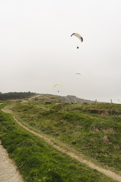 Parapente au-dessus des falaises verdoyantes par temps couvert