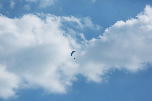 Parapente bleu volant dans le ciel avec des nuages par une journée ensoleillée