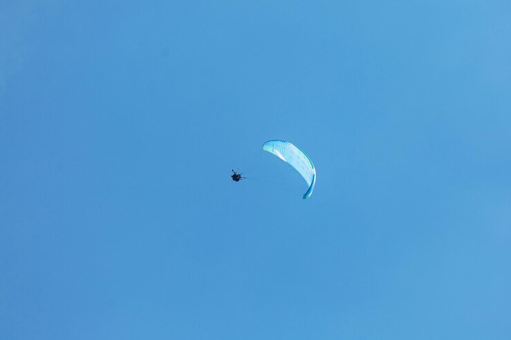 Photo parapente bleu volant dans le ciel avec des nuages par une journée ensoleillée