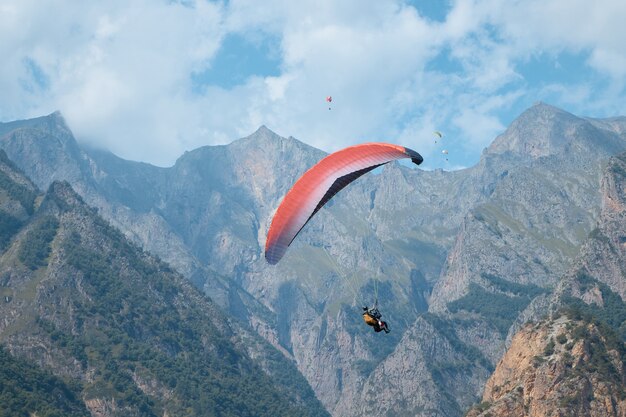 Parapente dans les airs, sports, parachute sur fond de montagnes, rochers, brouillard, nuages