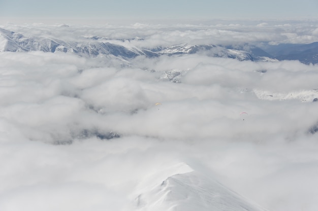 Parapente dans un ciel bleu nuageux sur les montagnes