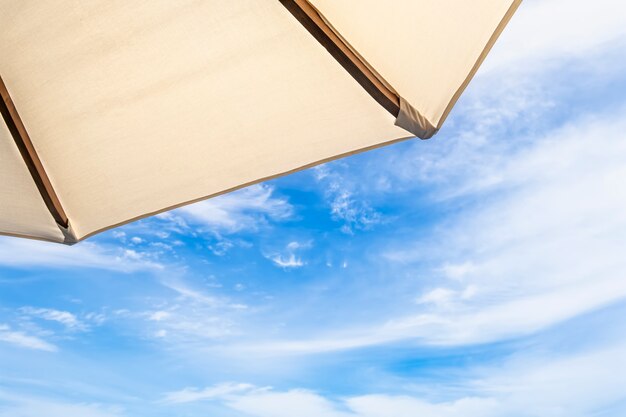 Parapluie blanc sur ciel bleu avec des nuages