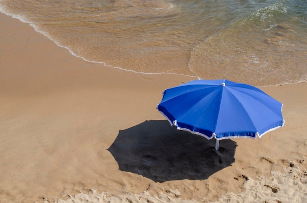 Parapluie bleu sur le sable de la plage