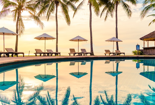 Parapluie et chaise autour de la piscine dans un hôtel de villégiature pour les voyages d'agrément et les vacances près de la mer