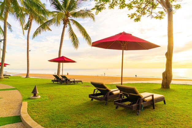 Parapluie avec chaise avec fond de plage de mer et lever de soleil le matin - concept de vacances et de vacances