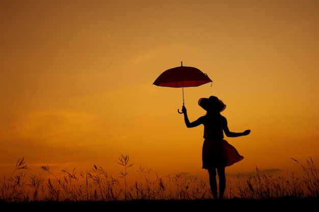 Parapluie Femme silhouette debout et coucher de soleil