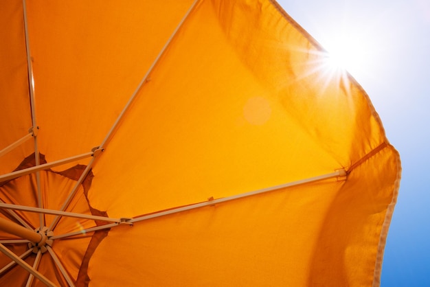 Parapluie jaune contre le soleil et le ciel bleu