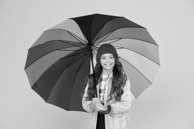 Le parapluie ne peut pas arrêter la pluie Heureux petit enfant en imperméable porter un parapluie contre la pluie Mignonne petite écolière se cacher sous un parapluie par temps de pluie humide Cela la fait se tenir debout sous la pluie