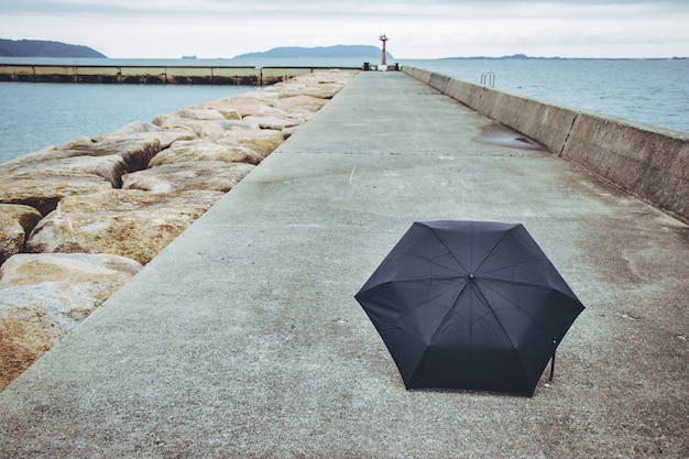 Photo parapluie noir sur le chemin du sentier. près de la mer.