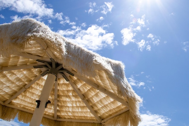 Parapluie de paille blanche sur la plage contre le ciel