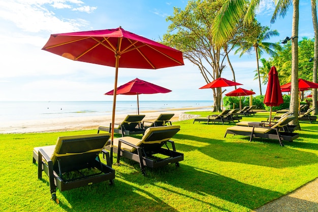 Parapluie rouge et chaise de plage avec fond de plage de mer et ciel bleu et soleil
