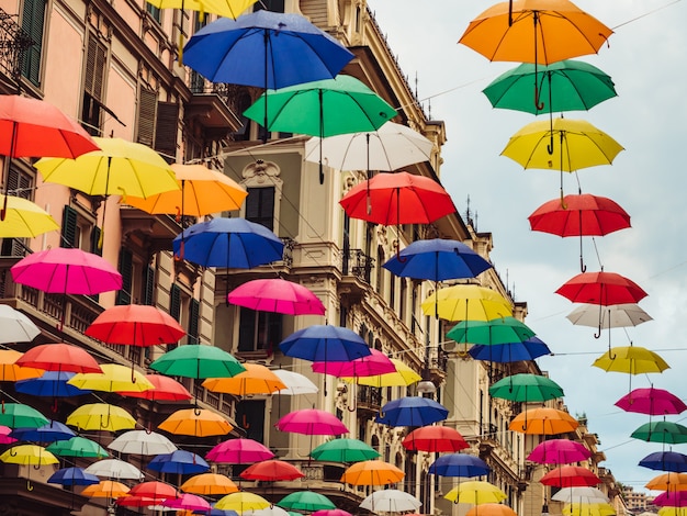 Parapluies multicolores et lumineux suspendus entre les maisons