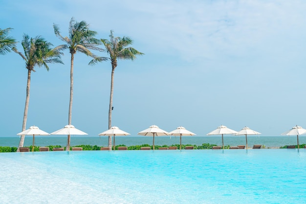 parasol avec lit piscine autour de la piscine avec fond de mer océan - concept de vacances et de vacances