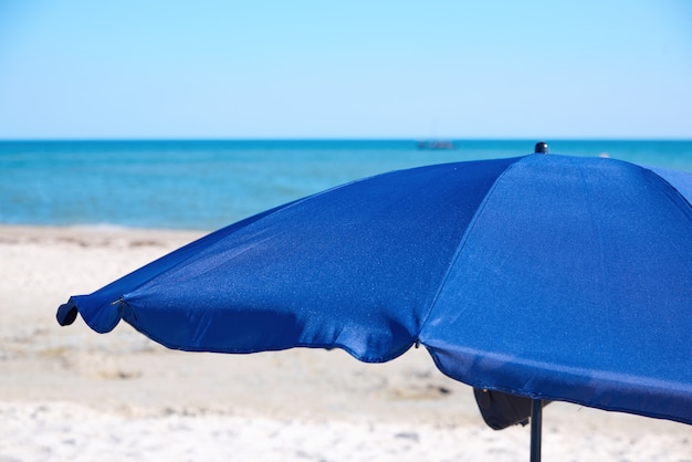 Parasol ouvert bleu textile sur une plage de sable