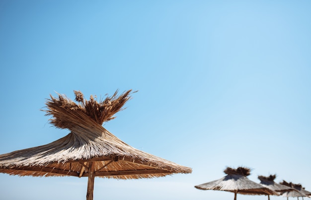 Parasol en paille et en bois sur ciel bleu