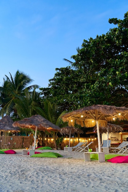 Parasol de plage en feuilles de palmier séchées sur une plage de l'île tropicale Un concept de vacances de luxe