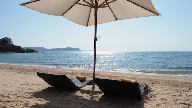 Parasol de plage de texture de tissu blanc et trépied en bois marron avec nuage blanc et ciel bleu clair