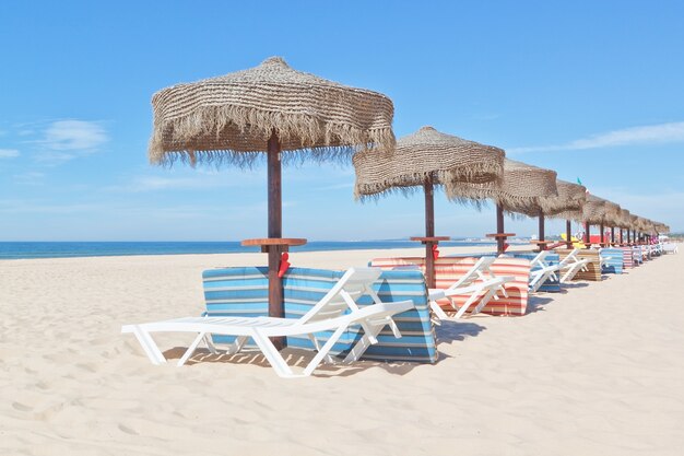 Parasols Et Transats En Bois Sur La Plage. Pour Les Vacances.