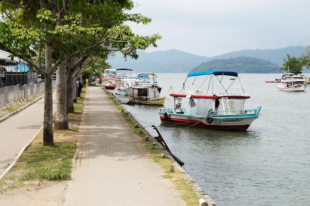 PARATY RIO DE JANEIRO SEPTEMBRE 25 2023 Petits bateaux amarrés à côté d'une promenade bordée d'arbres à Paraty