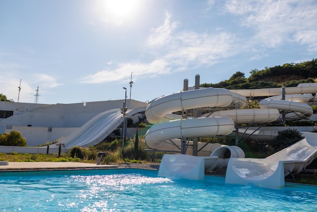 Parc aquatique vide avec de hauts toboggans blancs et des chaises longues blanches