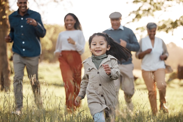 Photo parc en cours d'exécution et fille avec parents ou grands-parents sur terrain en herbe pour une aventure en liberté ou jouer en été hommes ou femmes de famille s'amusant ou aimant dans la forêt avec du soleil pour les soins ou le bonheur