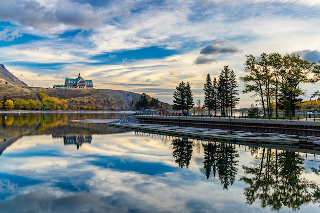 Parc national des Lacs-Waterton au bord du lac en automne matin. Ciel bleu, nuages colorés se reflètent sur la surface du lac comme un miroir au lever du soleil. Paysage de couleur d'automne. Monuments à Alberta, Canada