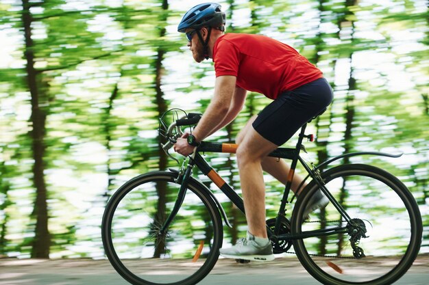 Parc naturel. Cycliste sur un vélo est sur la route goudronnée dans la forêt à la journée ensoleillée