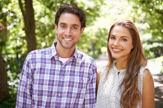 Photo parc portrait heureux et couple amoureux à un rendez-vous en plein air avec bonheur dans la nature vacances au soleil et jeune amusement avec un sourire en été en vacances se sentir se détendre au soleil avec un arrière-plan flou